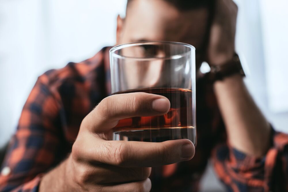 man staring at glass of alcohol