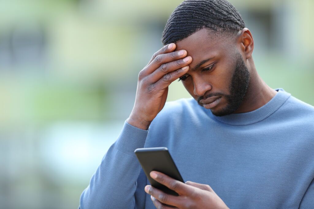 Stressed individual staring at their phone, reflecting the anxiety tied to fantasy football gambling